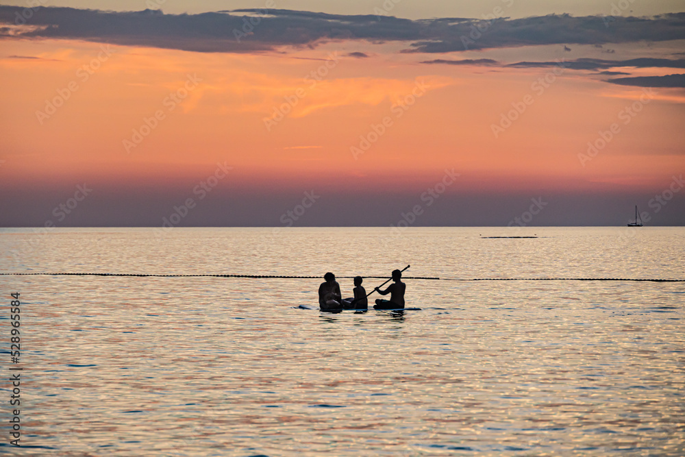 Fototapeta premium People on the sup sailing in the sunset