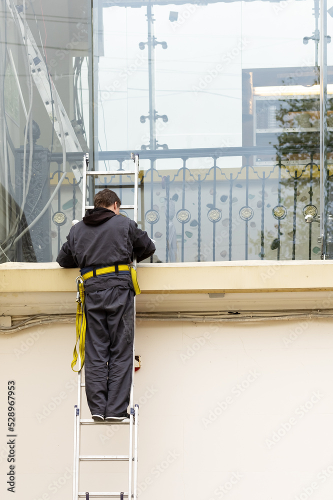 An electrician on a ladder performs work. Worker in work clothes on stairs