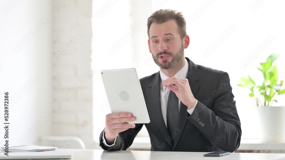 Young Businessman making Video Call on Tablet in Office Young Businessman making Video Call on Tablet in Office