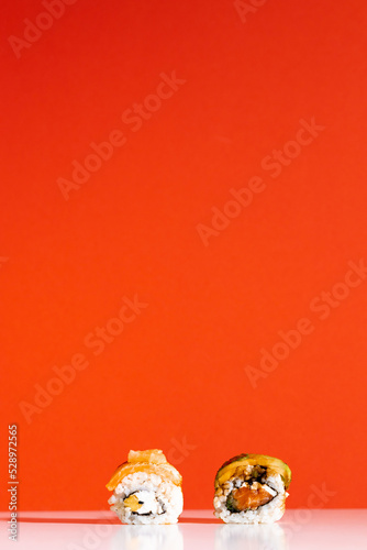 Delicious sushi rolls on red background