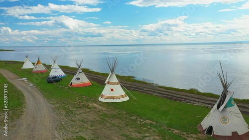 Aerial drone video, rotating from right to left revealing the landscape near the tipis facing a bay and the St-Lawrence River in Maria in Gaspesie, Quebec.