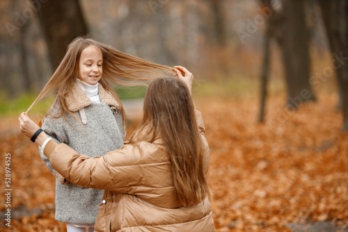 Mother and her daughter playing and having fun in autumn forest