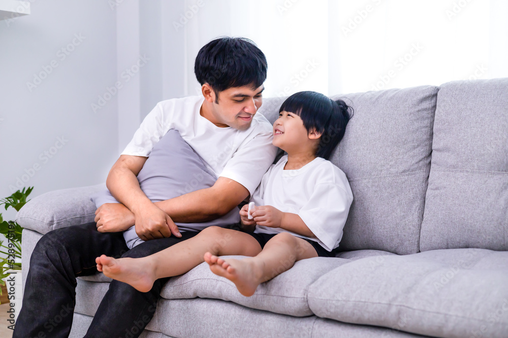 Happy dad sit relax on sofa in living room with his son laugh and smile, happy father rest on couch at home with son have fun on weekend enjoy time together. Family concept or communication concept.