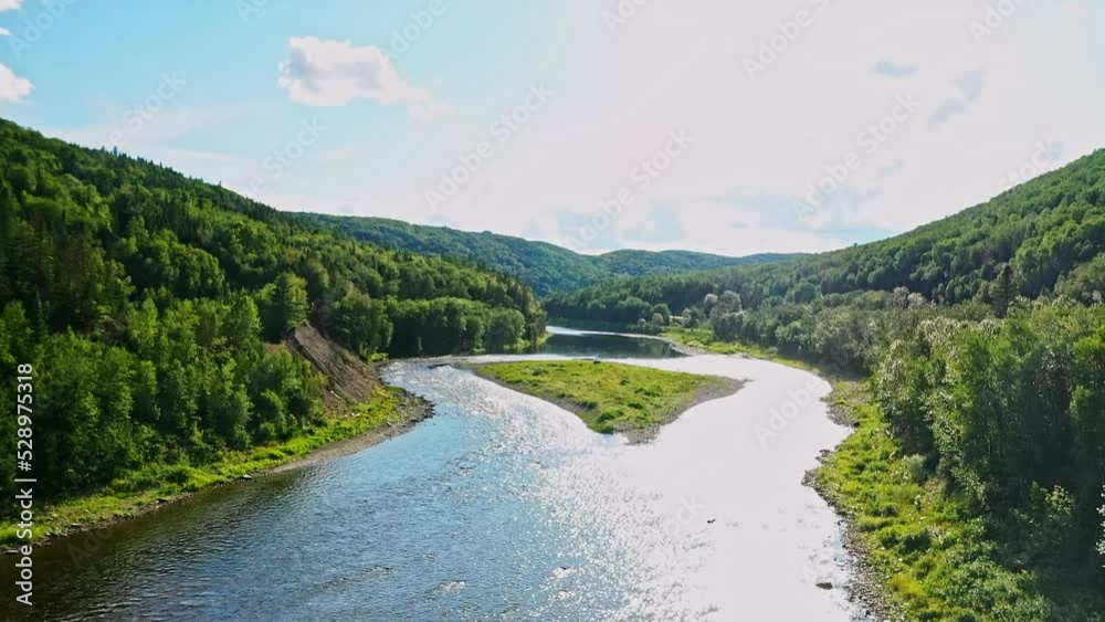 Aerial drone crane shot video above the river revealing the landscape with its mountains and forest in the Matapedia Valley in Gaspesie, Quebec. Aerial drone crane shot video above the river revealing the landscape with its mountains and forest in the Matapedia Valley in Gaspesie, Quebec.