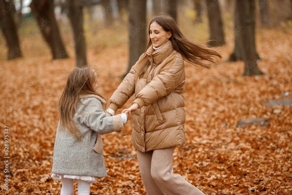 Mother and her daughter playing and having fun in autumn forest