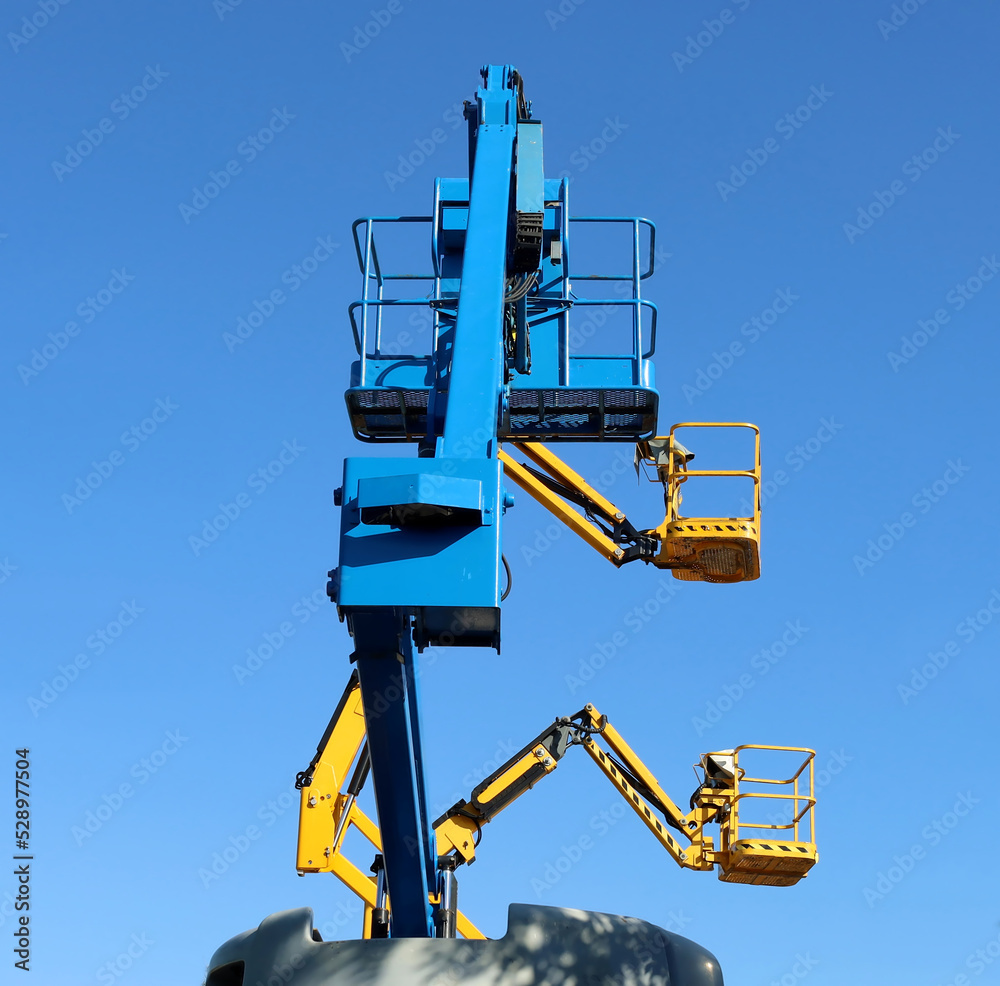 Three aerial working platforms of cherry picker against blue sky. Back side for the first one and side view for the others two. Three aerial working platforms of cherry picker against blue sky. Back side for the first one and side view for the others two.