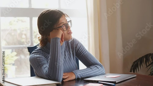 One beautiful female teenager sleeping and resting on the table while studying or working at home. Millennial taking a break after doing homework using laptop.
 photo