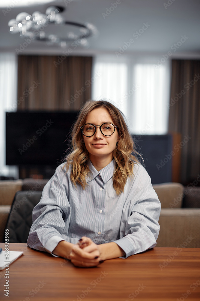 Female office worker wearing glasses sitting at desk on workplace. Job interview, hr, employment concept Female office worker wearing glasses sitting at desk on workplace. Job interview, hr, employment concept