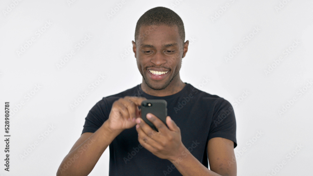 Young African Man Browsing Smartphone on White Background Young African Man Browsing Smartphone on White Background