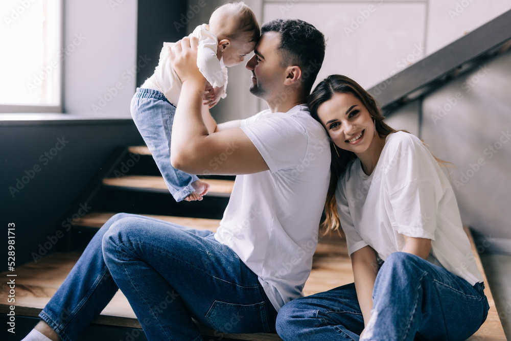 Young couple lying together on blankets on their living room floor at home with their adorable baby daughter Young couple lying together on blankets on their living room floor at home with their adorable baby daughter