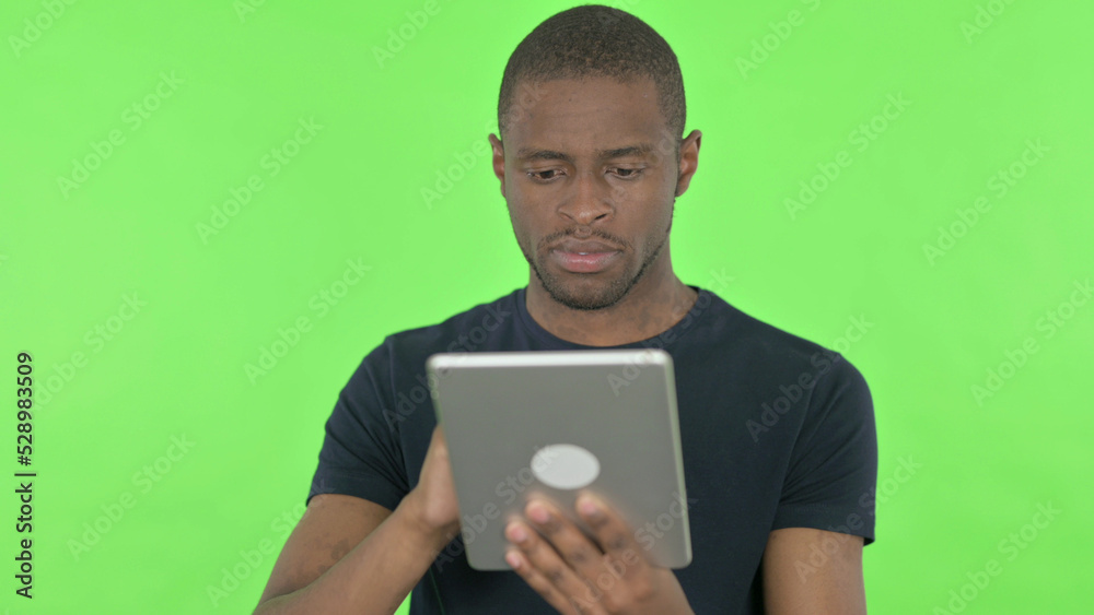 Young African Man using Digital Tablet on Green Background Young African Man using Digital Tablet on Green Background