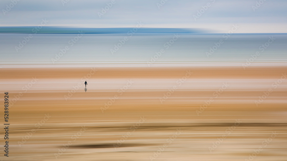 Obraz premium lonely, single walker on motion blurred peaceful beach and sea at Dunnet Bay Scotland