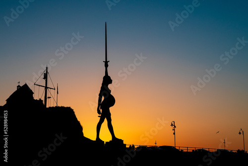 Sunset silhouette of pregnant woman verity sculpture landmark in Ilfracombe Devon with gold and blue sky photo