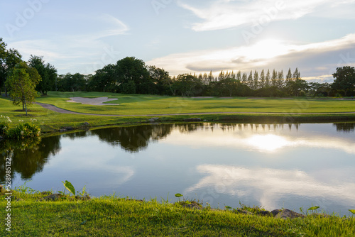 View of Golf Course with fairway and pond at sunset, Golf course with a rich green turf beautiful scenery, Green grass and woods on a golf field