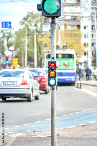 Riga, Latvia - May 13, 2022: Small traffic semaphore with green light against the backdrop of the city traffic.