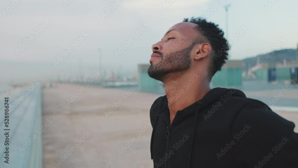 Young bearded male athlete doing warm-up, head rotation before training while standing on the embankment Young bearded male athlete doing warm-up, head rotation before training while standing on the embankment