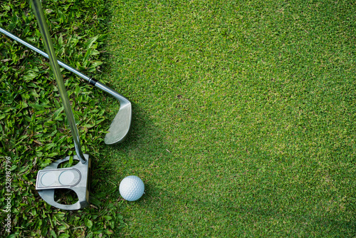 Golf clubs and golf balls on a green lawn in a beautiful golf course.
