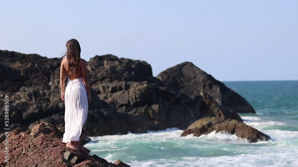 Happy young brunette woman at the top cliff of the beach with white dress outfit Happy young brunette woman at the top cliff of the beach with white dress outfit