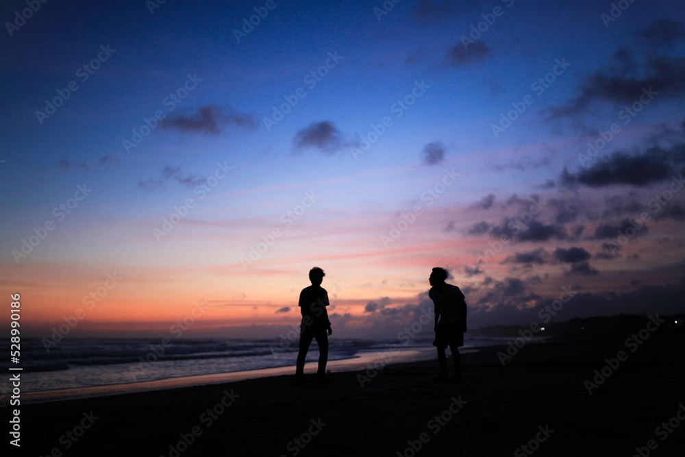 silhouette of two men standing at sunset