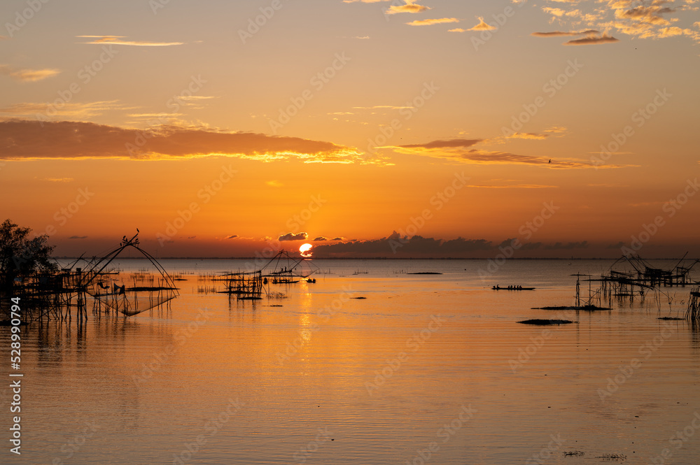 Square dip net in lake with sunrise at Pak pra village, Phatthalung, Thailand Square dip net in lake with sunrise at Pak pra village, Phatthalung, Thailand