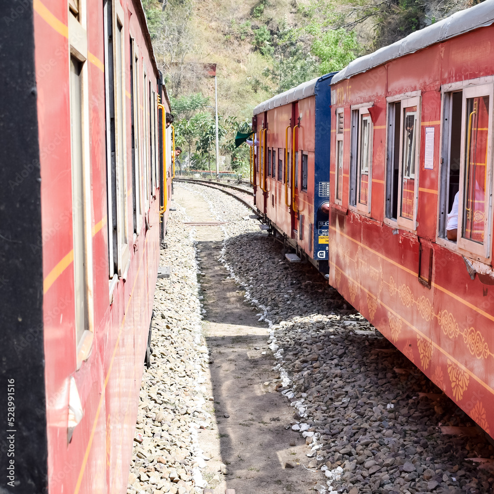 Obraz premium Toy Train moving on mountain slopes, beautiful view, one side mountain, one side valley moving on railway to the hill, among green natural forest. Toy train from Kalka to Shimla in India, Indian Train