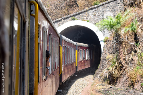 Toy Train moving on mountain slopes, beautiful view, one side mountain, one side valley moving on railway to the hill, among green natural forest. Toy train from Kalka to Shimla in India, Indian Train photo