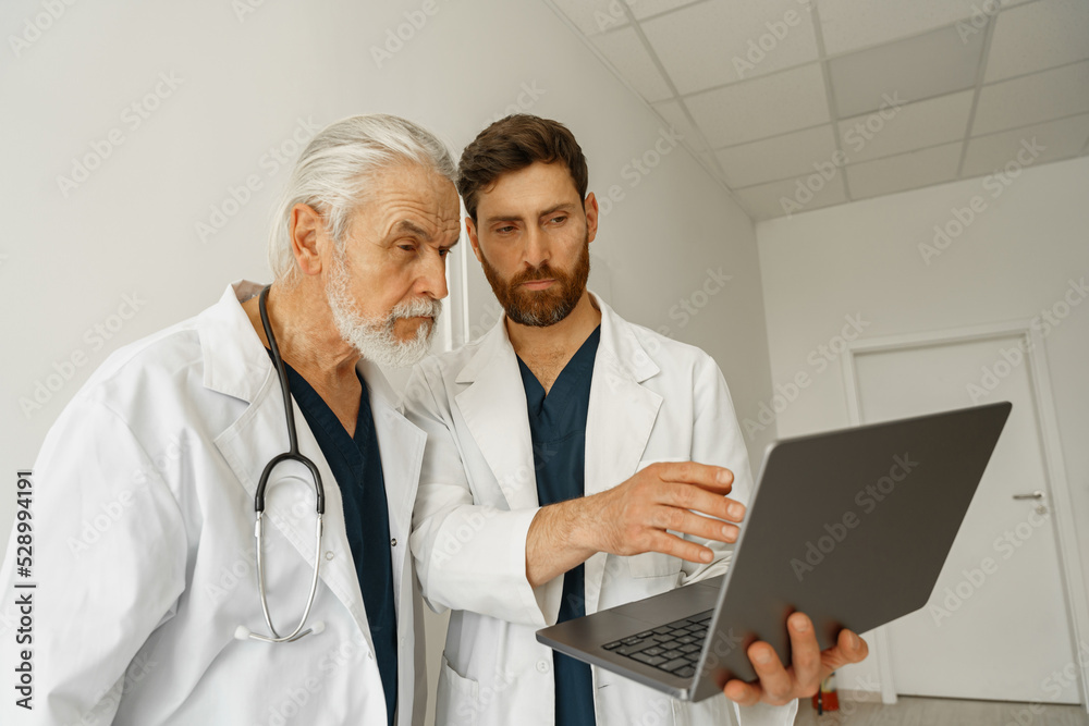 Two doctor colleagues discussing patient diagnosis stand in medicine clinic hall Two doctor colleagues discussing patient diagnosis stand in medicine clinic hall