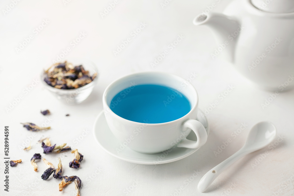 Thai blue Anchan tea in a white cup and teapot on a wooden background.