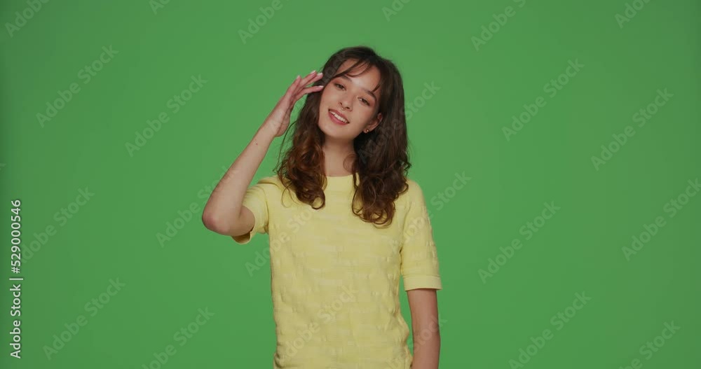 Friendly cool young girl makes honor gesture, saluting, showing respect on chromakey green studio background Friendly cool young girl makes honor gesture, saluting, showing respect on chromakey green studio background