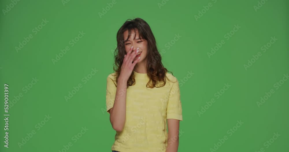 Laughing girl having fun, giggling at a joke on green chromakey studio background. Humor, comedy, positive emotions Laughing girl having fun, giggling at a joke on green chromakey studio background. Humor, comedy, positive emotions