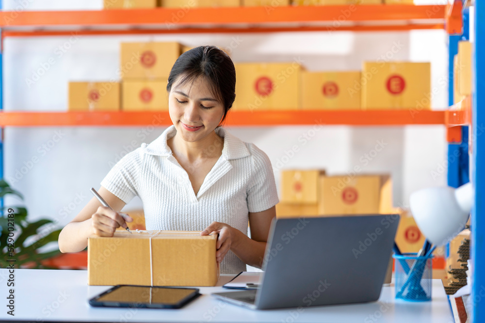 SME entrepreneur Small business entrepreneurs Online selling ideas,Happy Young Asian business owner work on computer and a boxs at home,delivery SME procurement package box deliver to customers SME entrepreneur Small business entrepreneurs Online selling ideas,Happy Young Asian business owner work on computer and a boxs at home,delivery SME procurement package box deliver to customers