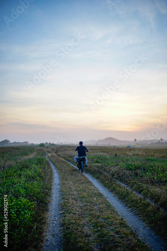 motorbike users use footpaths in the meadow with a mountain background © adelukmanulhakim