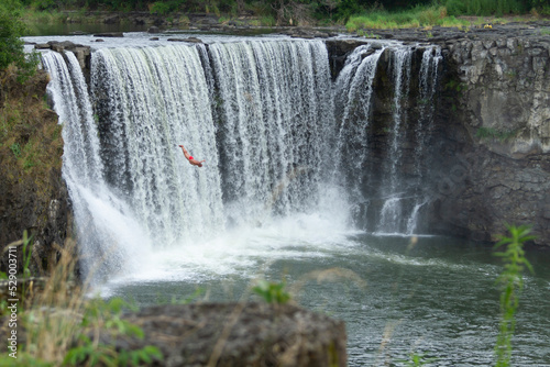 A men is diving from a cliff at Jingbo Lake falls in Heilongjiang  China. Waterfall and Mountain landscape.