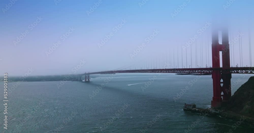 Well-known famous San Francisco landmark Golden Gate bridge. Upper parts of bridge are in fog. Boat sailing under the bridge. Well-known famous San Francisco landmark Golden Gate bridge. Upper parts of bridge are in fog. Boat sailing under the bridge.