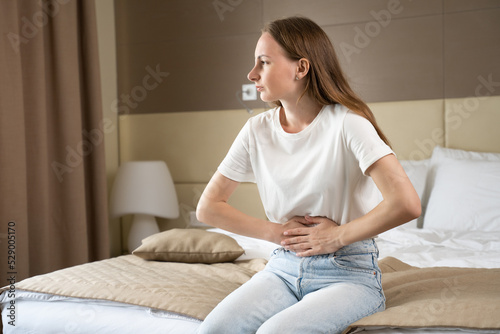 фотографія Upset woman touching belly has bad stomachache