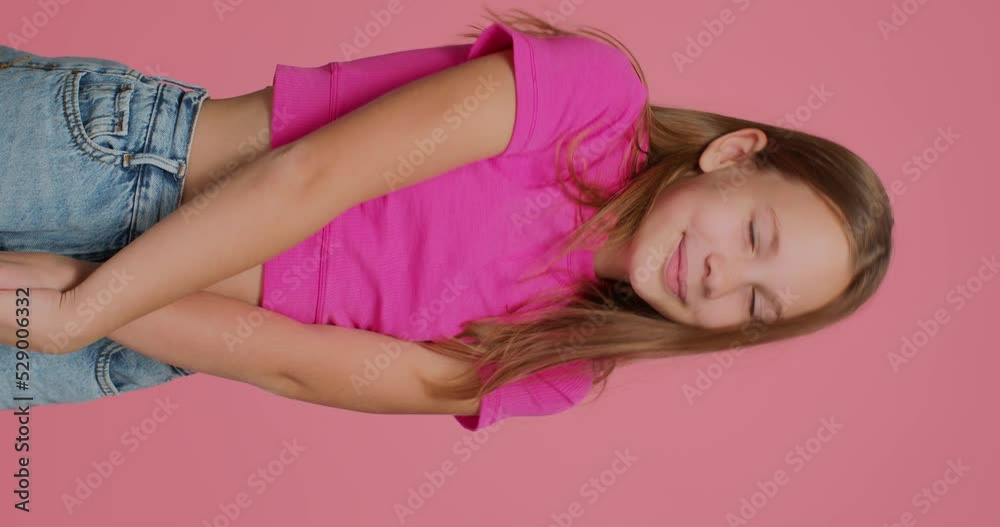 Cute embarrassed shy child girl blogger showing embarrassment gesture by forefingers, shooting vertical video
