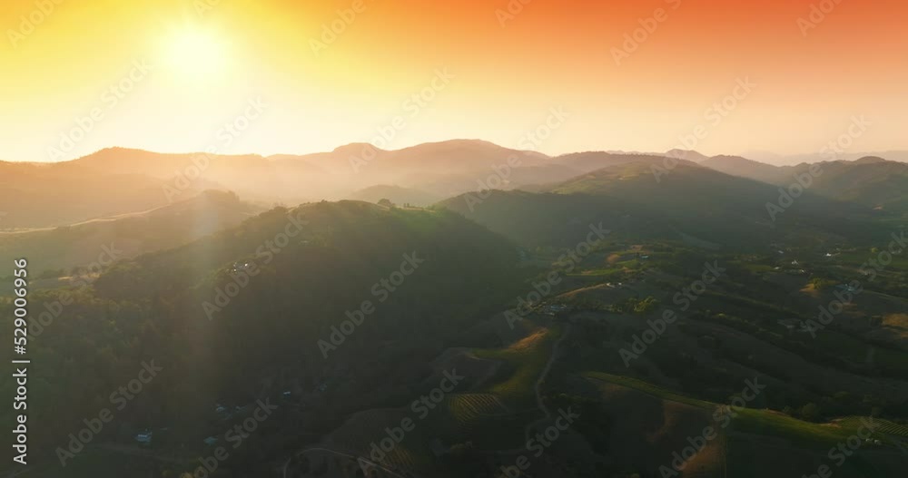 Picturesque green mountains of Napa, California, USA. Amazing vineyards from aerial perspective at setting sun. Orange sky at backdrop.