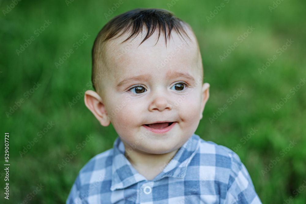 Portrait of little smiling boy in park. Close-up. Toddler boy walks in park. Brown eyes. Portrait of little smiling boy in park. Close-up. Toddler boy walks in park. Brown eyes.