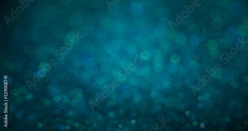 Defocused glow background. Bokeh circles texture. Shiny bubbles. Blur green blue particles glare on dark abstract overlay. © golubovy