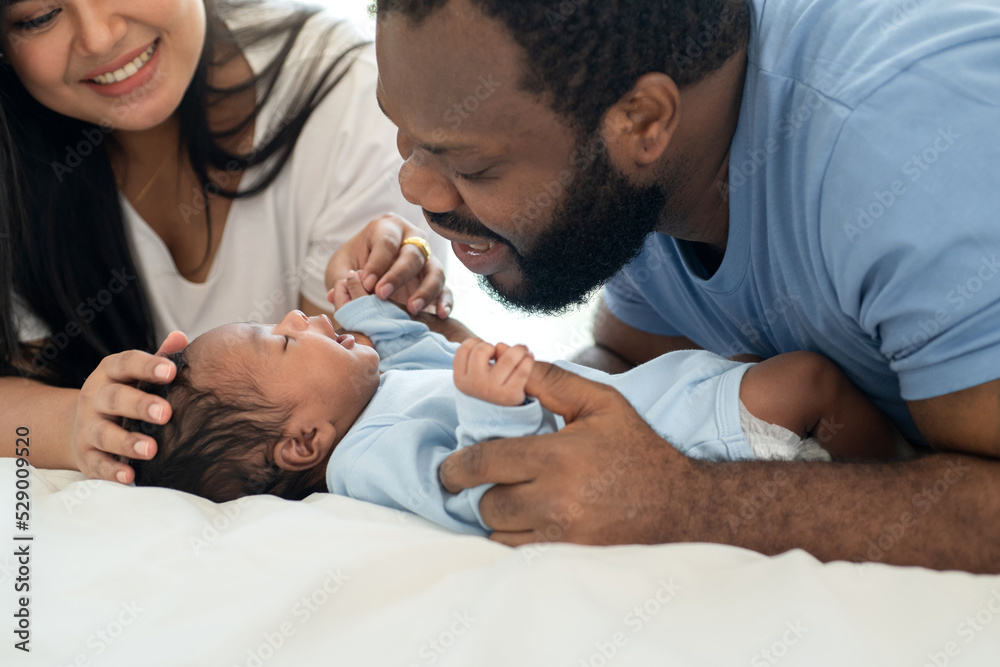 Happy African family hugs and kisses cute little son, African daddy and mom and little baby enjoying time together at home Happy African family hugs and kisses cute little son, African daddy and mom and little baby enjoying time together at home