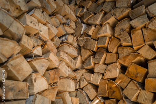 Split birch firewood for heating the home stove and fireplace in winter. Wooden wall from pile of firewood stacked in an shed. Preparation of the stock of firewood for the winter period. Selective