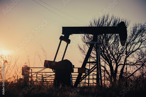 An oil pump jack in rural Texas at sunset outside of Montague County.  photo