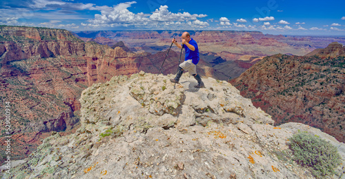 A hiker on the edge of a cliff along Buggeln Hill Trail halfway between Grandview Point and the Sinking Ship at Grand Canyon Arizona. photo