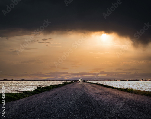 Car on a road between the sea with a dramatic sunset background 