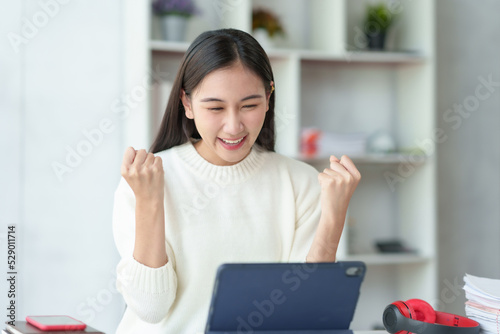 Pretty young Asian businesswoman sitting on a laptop Glad that the work came out, achieved the desired goal and was happy and satisfied with the results..