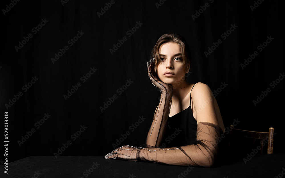 portrait of a graceful woman in a black dress and long gloves on a black background with a beautiful evening makeup looking pleasantly into the camera portrait of a graceful woman in a black dress and long gloves on a black background with a beautiful evening makeup looking pleasantly into the camera