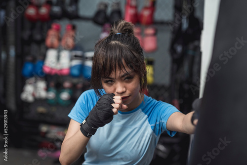 An active and energetic MMA trainee puts on a game face and begins her weekly workout with throwing some punches on the heavy bag. photo