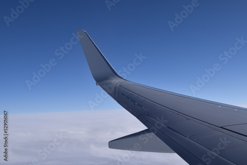 Window view of an airplane in the sky over clouds. Blue sky in the background. Traveling concept