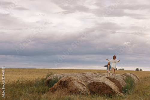 Fototapeta Naklejka Na Ścianę i Meble -  Mom and daughter are sitting on haystacks