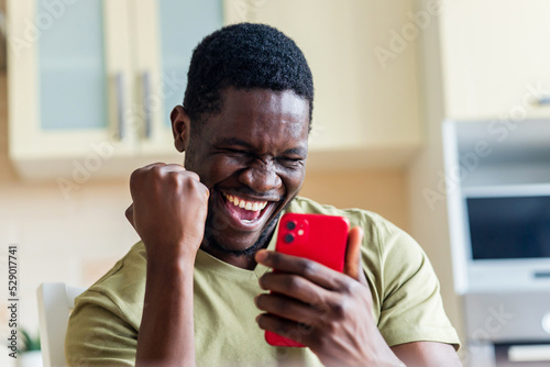 happy afro american man winner excited by mobile app with joy